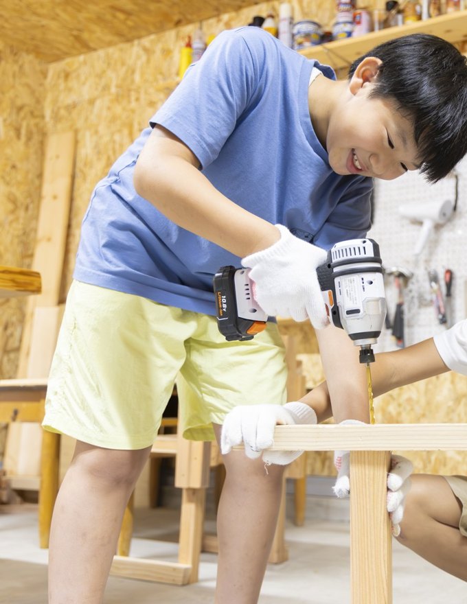 ドリルを持ち作業する少年